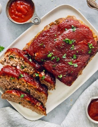 Overhead view of air fryer meatloaf on platter with three slices cut