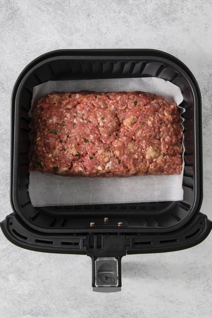 This Air Fryer Meatloaf gives you a classic comfort food meal — without the hassle of an oven. Tender and juicy, with the perfect glaze! Overhead view of raw meatloaf in air fryer