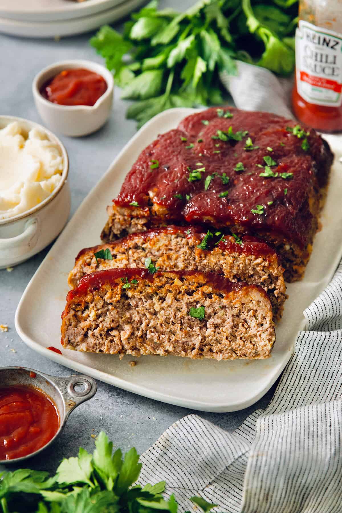This Air Fryer Meatloaf gives you a classic comfort food meal — without the hassle of an oven. Tender and juicy, with the perfect glaze! Sliced air fryer meatloaf on platter