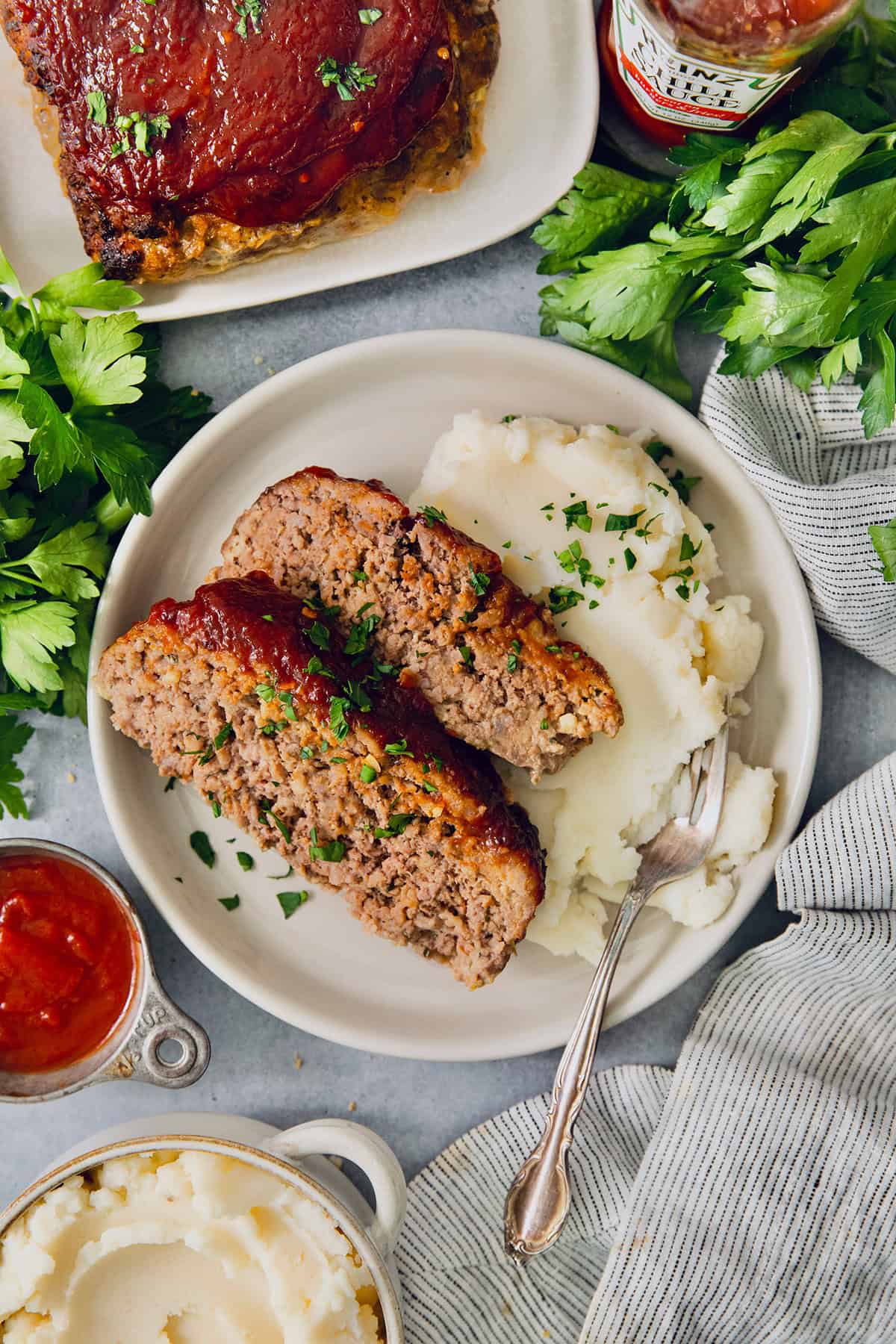 This Air Fryer Meatloaf gives you a classic comfort food meal — without the hassle of an oven. Tender and juicy, with the perfect glaze! Overhead view of air fryer meatloaf on plate with mashed potatoes