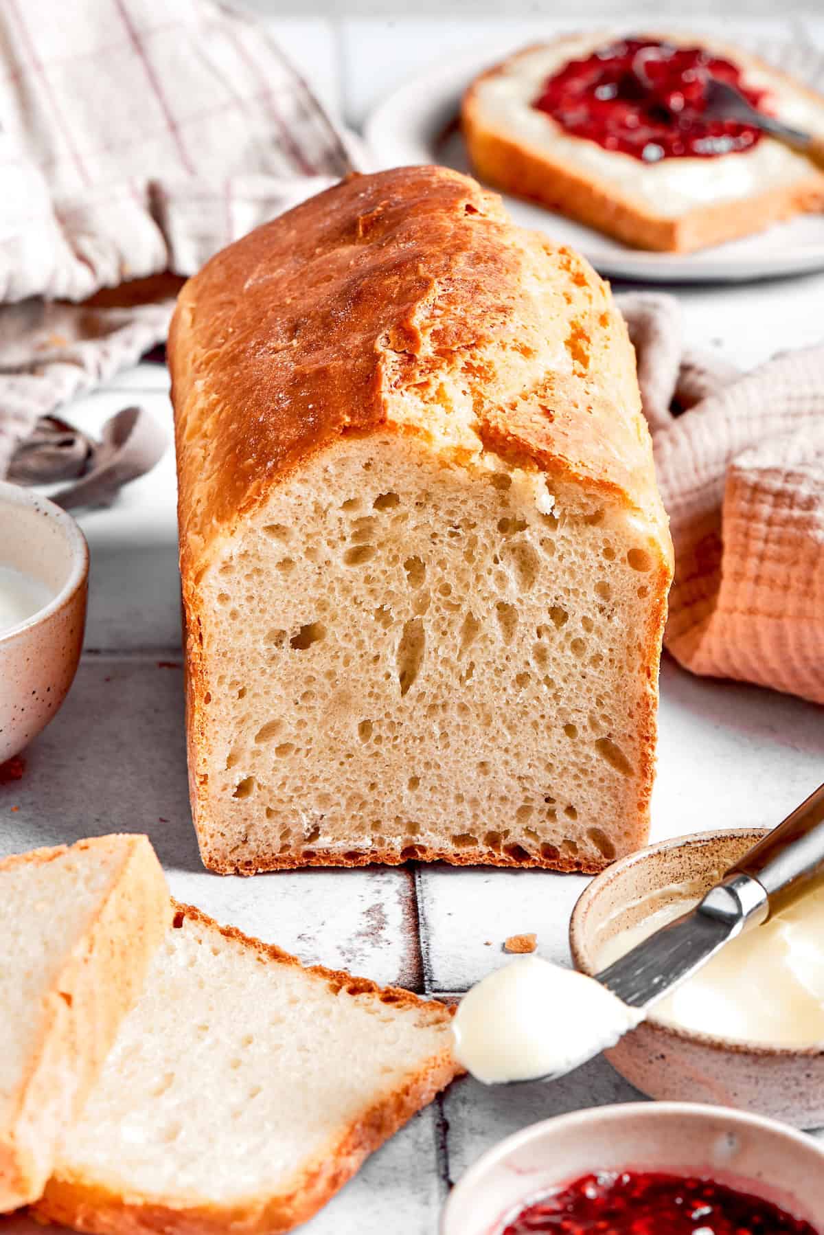 This homemade English Muffin Bread is incredibly easy, with no kneading required, and it will make your morning toast extra delicious! Loaf of English muffin bread on countertop with a few slices cut