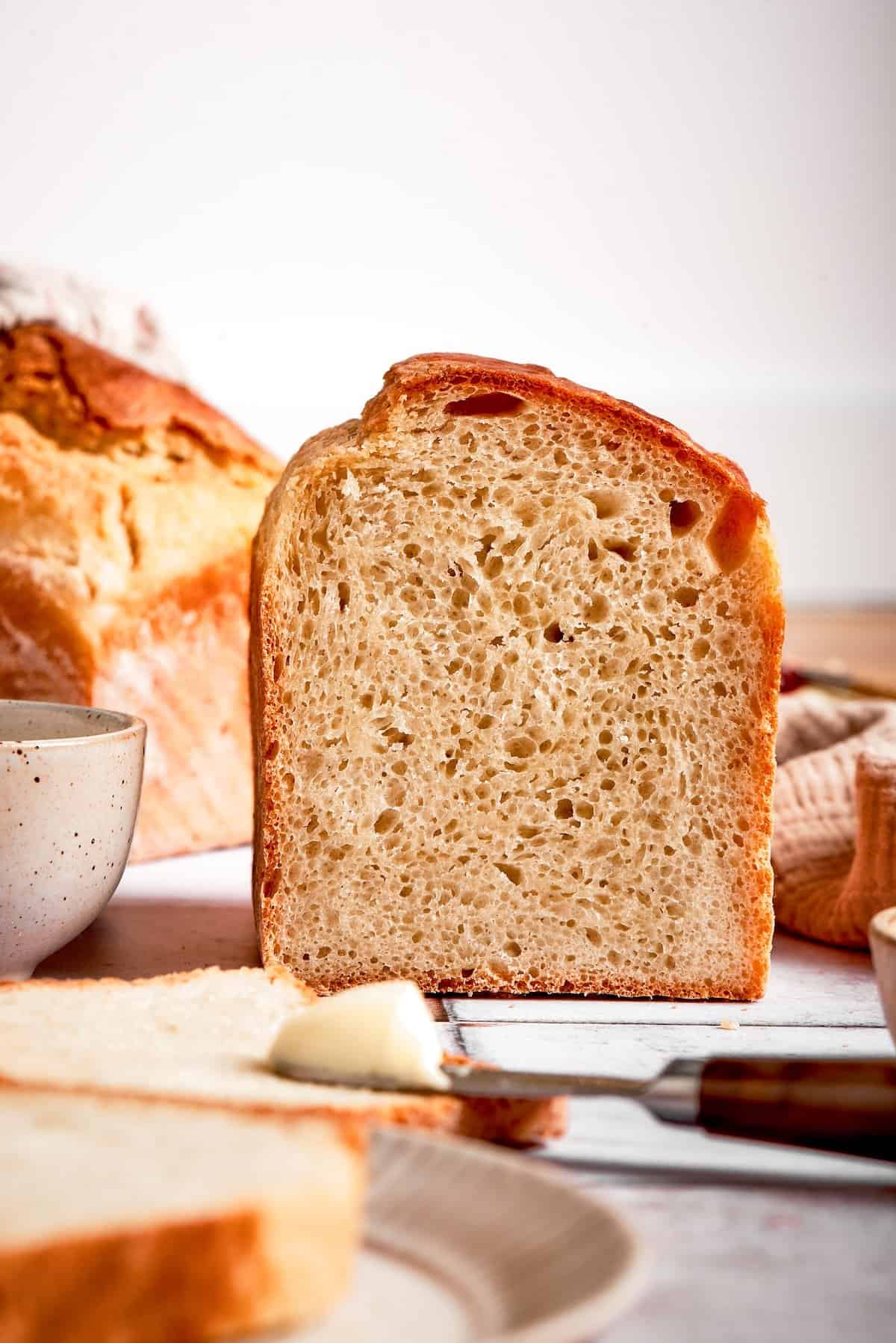 This homemade English Muffin Bread is incredibly easy, with no kneading required, and it will make your morning toast extra delicious! Side view of sliced English muffin bread, showing lofty height and crumb texture