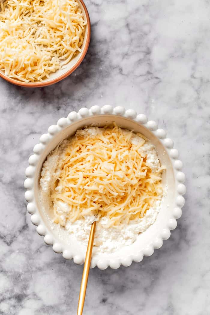 Lasagna beans pair creamy gigante beans with zippy tomato sauce, Italian sausage and ricotta, and it's all topped with even more cheese. Yum! Mixing mozzarella into bowl of cheesy yum
