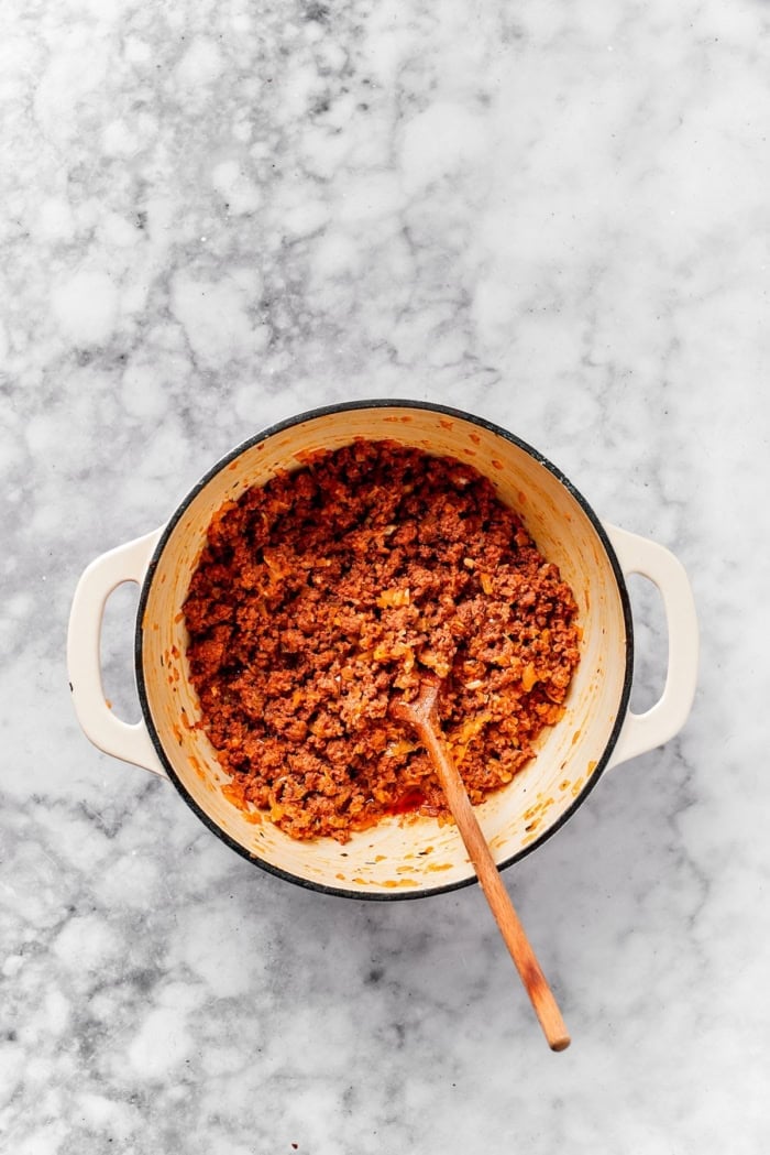 Lasagna beans pair creamy gigante beans with zippy tomato sauce, Italian sausage and ricotta, and it's all topped with even more cheese. Yum! Overhead view of Italian sausage and onions browning in pot