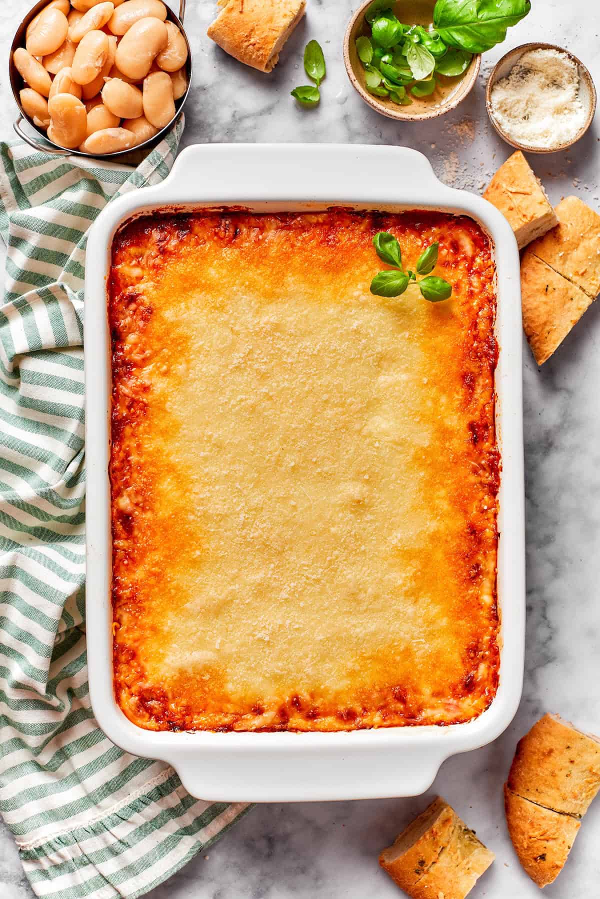 Lasagna beans pair creamy gigante beans with zippy tomato sauce, Italian sausage and ricotta, and it's all topped with even more cheese. Yum! Overhead view of lasagna beans in casserole dish
