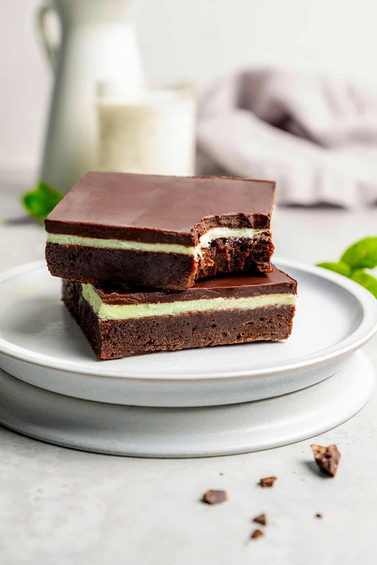two layered chocolate mint brownies on a plate, one with a bite out of it