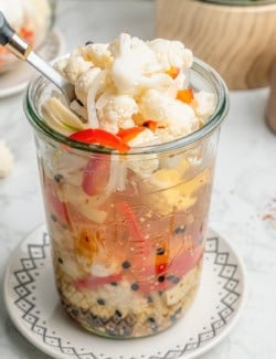 a fork scooping pickled cauliflower out of a jar
