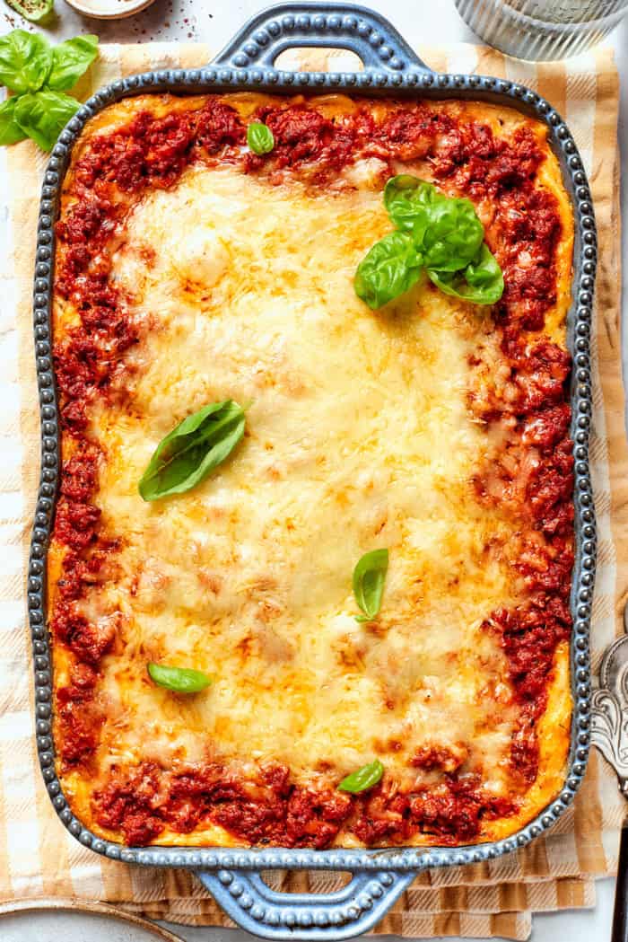 Meaty sauce, super fun spaghetti noodles, and pockets of Cheesy Yum make this Spaghetti Casserole an instant hit with the whole family! overhead photo of baked spaghetti casserole in a rectangular blue baking dish