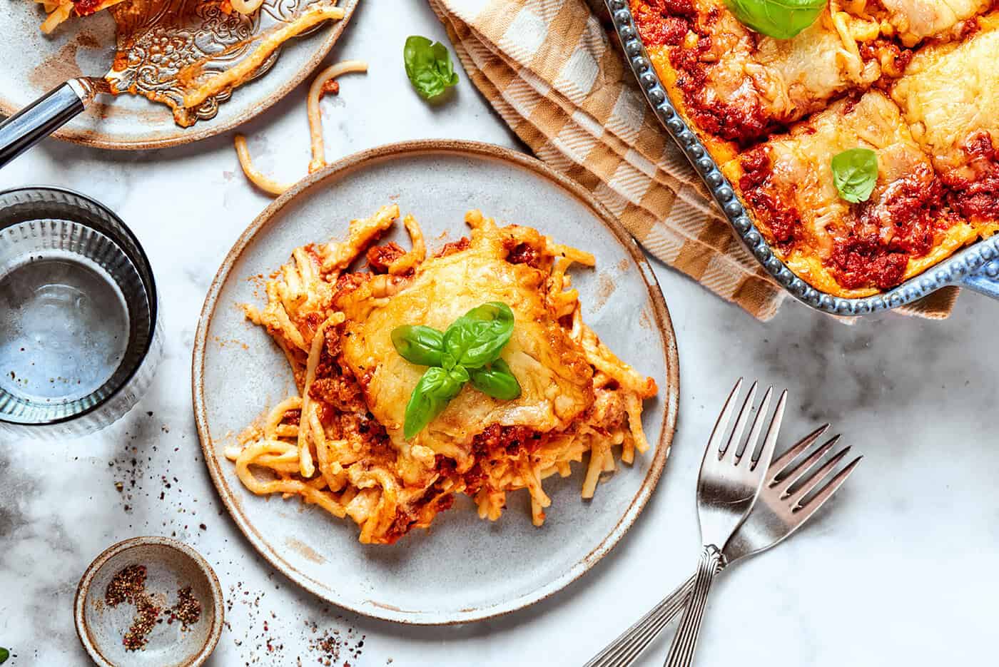 Meaty sauce, super fun spaghetti noodles, and pockets of Cheesy Yum make this Spaghetti Casserole an instant hit with the whole family! an individual serving of spaghetti casserole on a plate