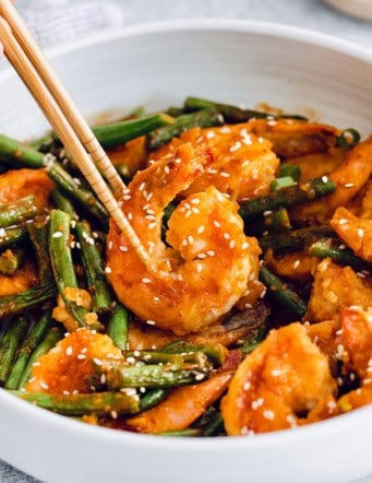 Chopsticks picking up Hunan shrimp from bowl