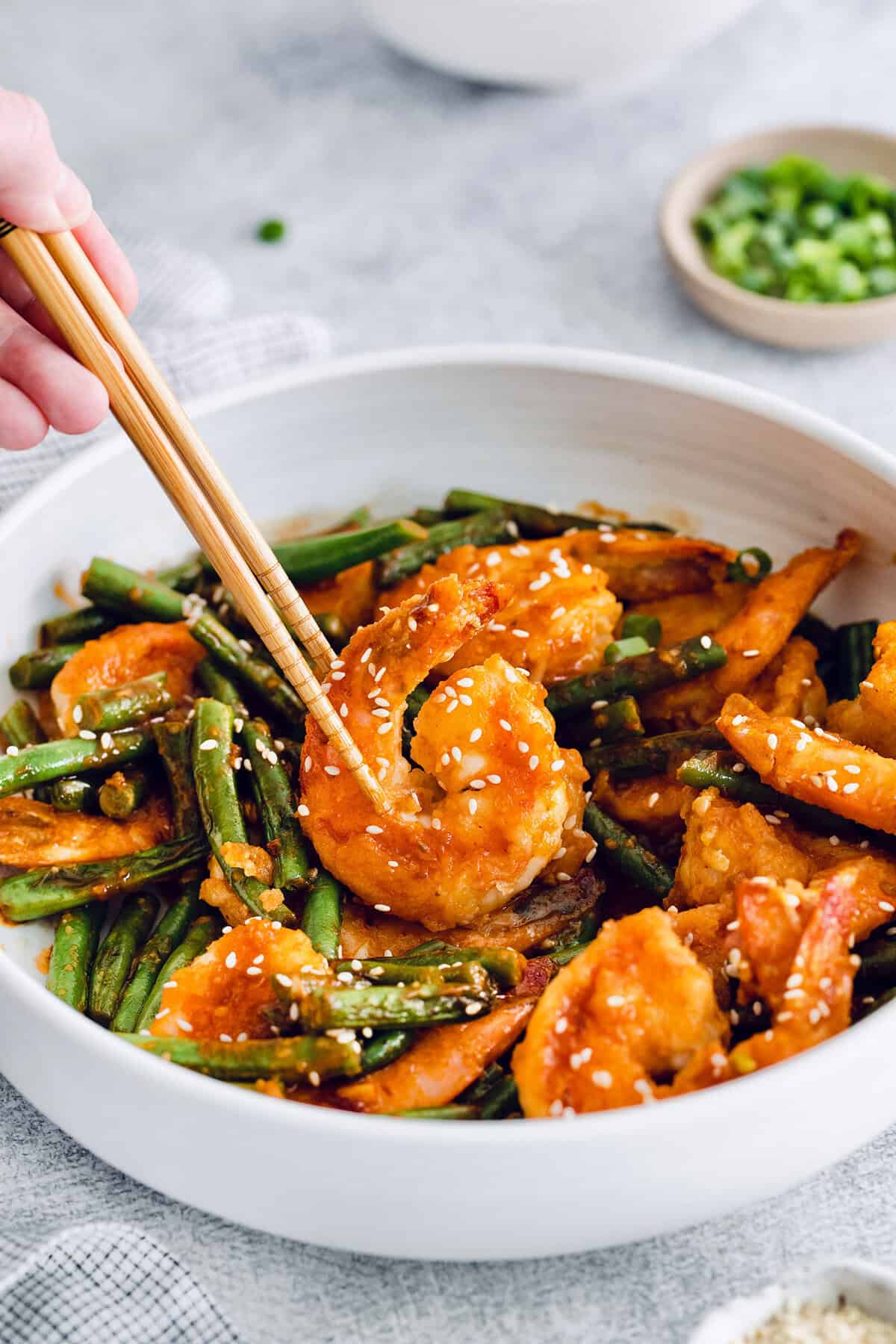 Chopsticks picking up Hunan shrimp from bowl