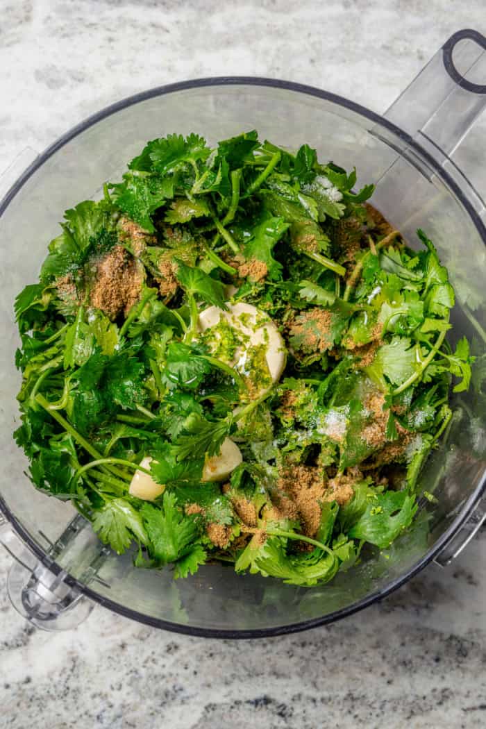 This easy Cilantro Lime Vinaigrette recipe is boldly herbaceous, brightly flavored with fresh lime, just a touch sweet and a bit garlicky. Overhead view of ingredients for cilantro lime vinaigrette in food processor