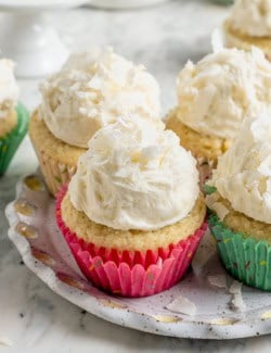 coconut cupcakes with mounds of fluffy coconut frosting, in pastel cupcake liners