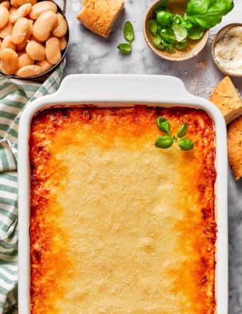 a white casserole dish of baked lasagna beans