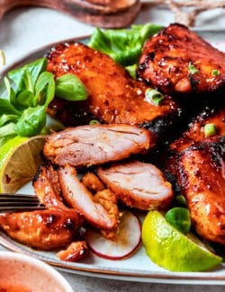 lemongrass chicken thighs on a platter, with one cut into pieces