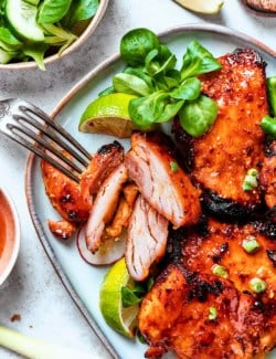 lemongrass chicken thighs on a platter, with one cut into pieces