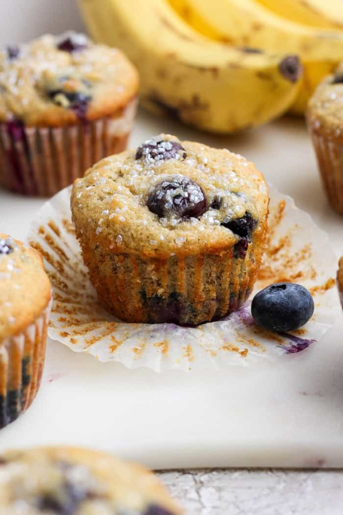 Banana Blueberry Muffins combine two classic recipes into one moist, lofty, perfectly sweet muffin package. They're such a treat! Closeup of banana blueberry muffin with wrapper pulled off