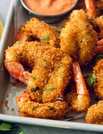 Crispy butterfly shrimp on metal tray with creamy cocktail sauce