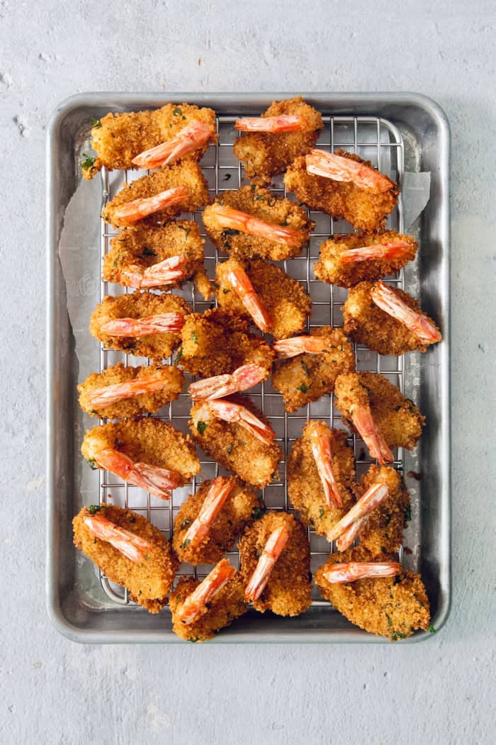 These butterfly shrimp are tender and juicy on the inside, crisp and crunchy on the outside, and paired with a spicy creamy cocktail sauce! Overhead view of butterfly shrimp draining after frying