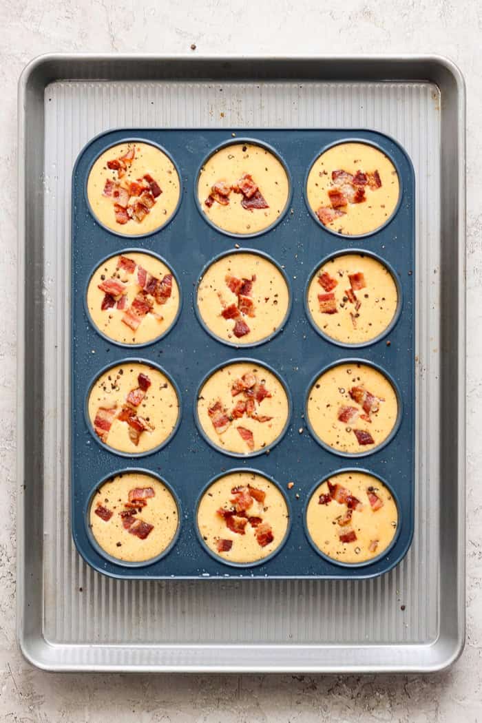 Cottage Cheese Egg Bites are creamy, cheesy and packed with protein. And let’s not forget the bacon! The perfect savory meal prep breakfast. Overhead view of unbaked cottage cheese egg bites in silicone pan