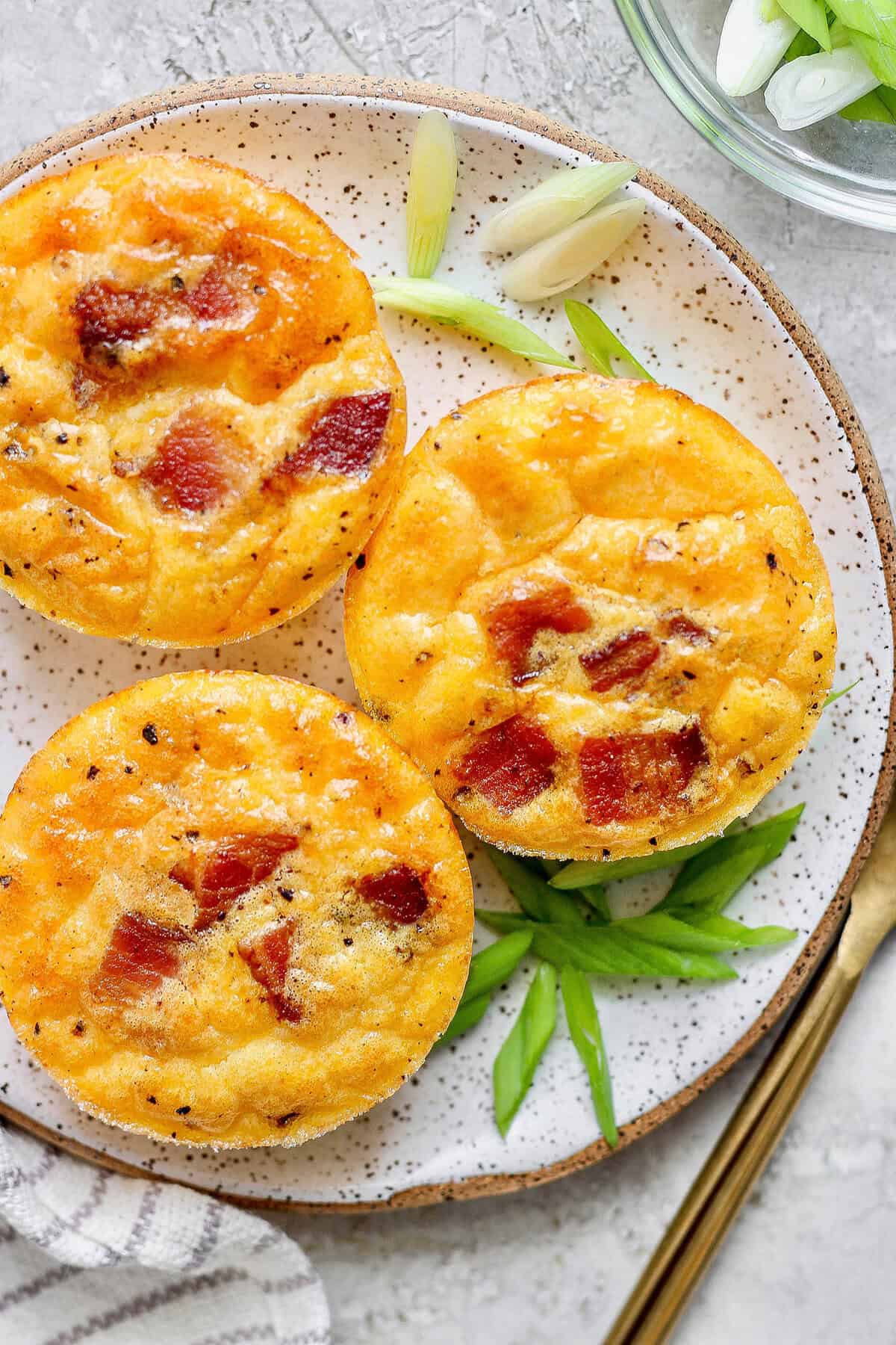 Cottage Cheese Egg Bites are creamy, cheesy and packed with protein. And let’s not forget the bacon! The perfect savory meal prep breakfast. Overhead view of 3 bacon cottage cheese bites on plate