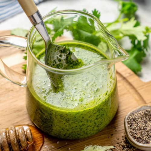 a small clear serving pitcher of cilantro lime vinaigrette