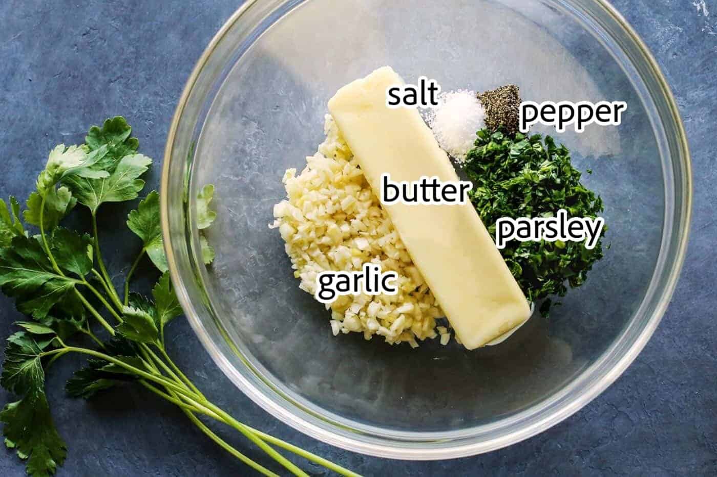 Cheesy garlic bread is the best, with buttery, toasted bread that's soft inside, crispy outside, and loaded with fresh herbs and melty cheese. Cheesy garlic bread ingredients with text labels overlaying each ingredient.