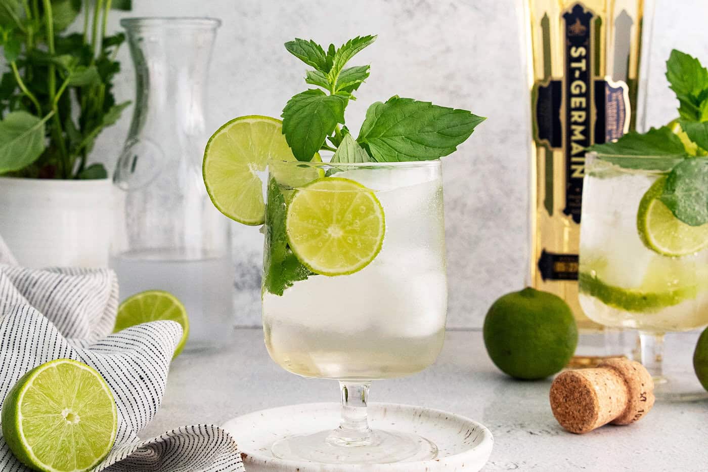 This fizzy Hugo spritz is easy to make, with a crisp, refreshing flavor and a little bit of floral complexity thanks to elderflower liqueur. Hugo spritz cocktail in glass with sprig of mint and lime wheels