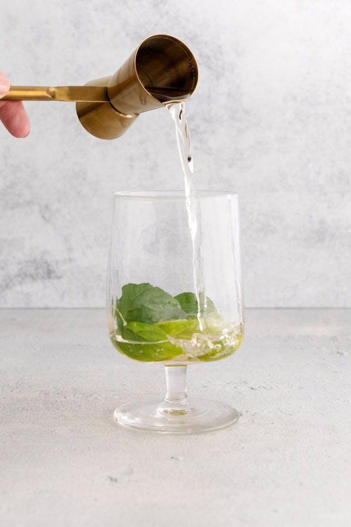This fizzy Hugo spritz is easy to make, with a crisp, refreshing flavor and a little bit of floral complexity thanks to elderflower liqueur. Pouring St-Germain into glass with lime wheels and mint