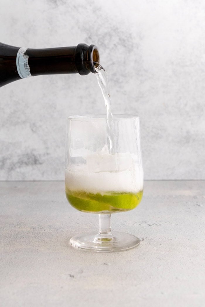 This fizzy Hugo spritz is easy to make, with a crisp, refreshing flavor and a little bit of floral complexity thanks to elderflower liqueur. Pouring prosecco into glass for Hugo spritz cocktail