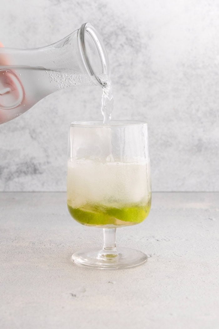This fizzy Hugo spritz is easy to make, with a crisp, refreshing flavor and a little bit of floral complexity thanks to elderflower liqueur. Pouring club soda into glass for Hugo spritz