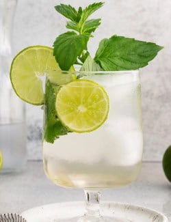 Hugo spritz cocktail in glass with lime wheels and mint sprigs