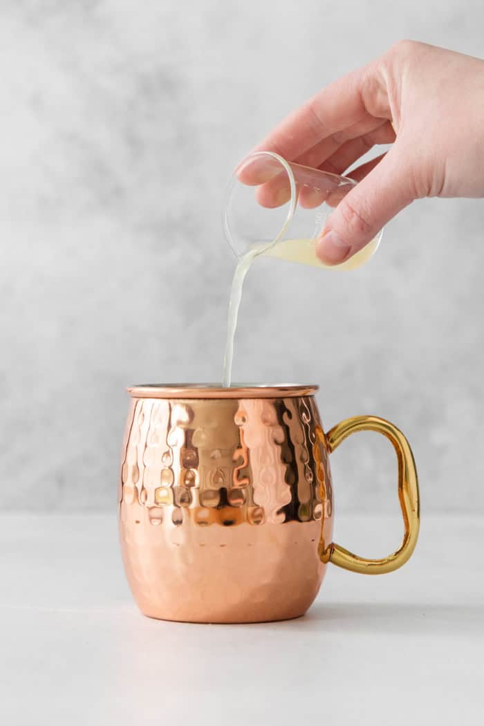 This easy Moscow Mule Mocktail has the bold ginger, tart lime and refreshing mint flavor you love, minus the alcohol. Perfect for summer! Pouring lime juice into copper mug