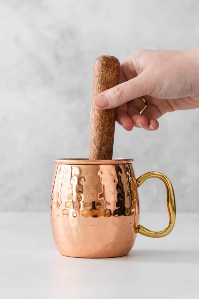This easy Moscow Mule Mocktail has the bold ginger, tart lime and refreshing mint flavor you love, minus the alcohol. Perfect for summer! Muddling ingredients in copper Moscow mule mug