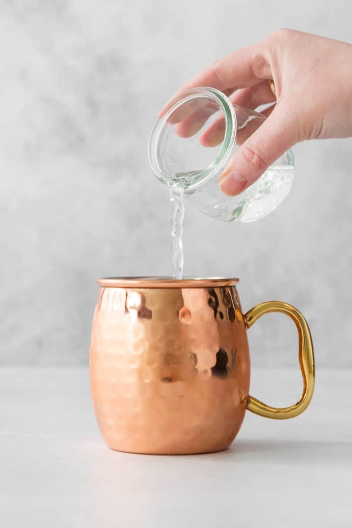This easy Moscow Mule Mocktail has the bold ginger, tart lime and refreshing mint flavor you love, minus the alcohol. Perfect for summer! Pouring club soda into copper mug
