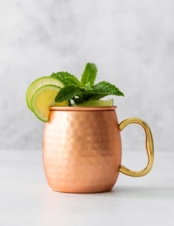 Copper mug with Moscow mule mocktail garnished with sprig of mint and lime