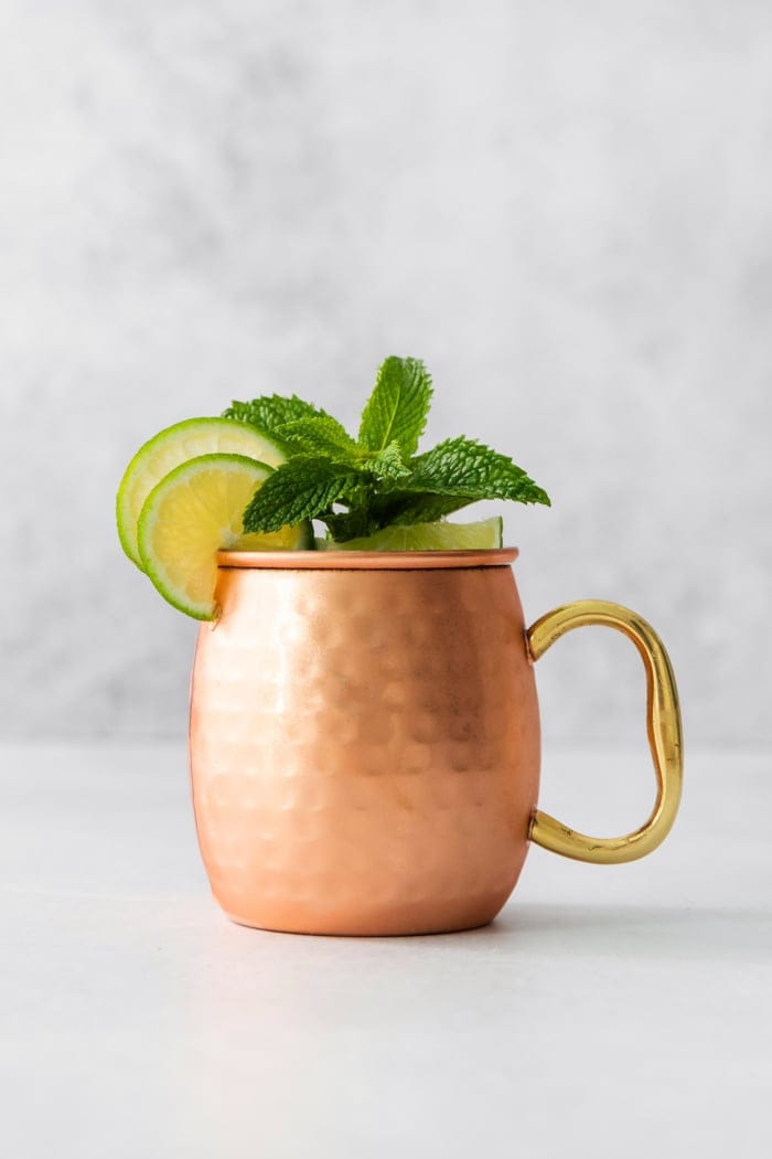 This easy Moscow Mule Mocktail has the bold ginger, tart lime and refreshing mint flavor you love, minus the alcohol. Perfect for summer! Copper mug with Moscow mule mocktail garnished with sprig of mint and lime