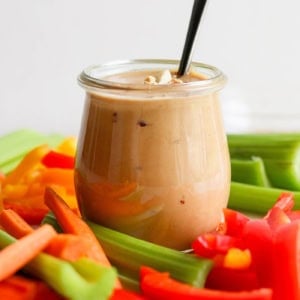 fresh cut vegetables with a jar of peanut sauce