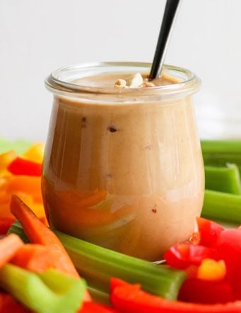 fresh cut vegetables with a jar of peanut sauce