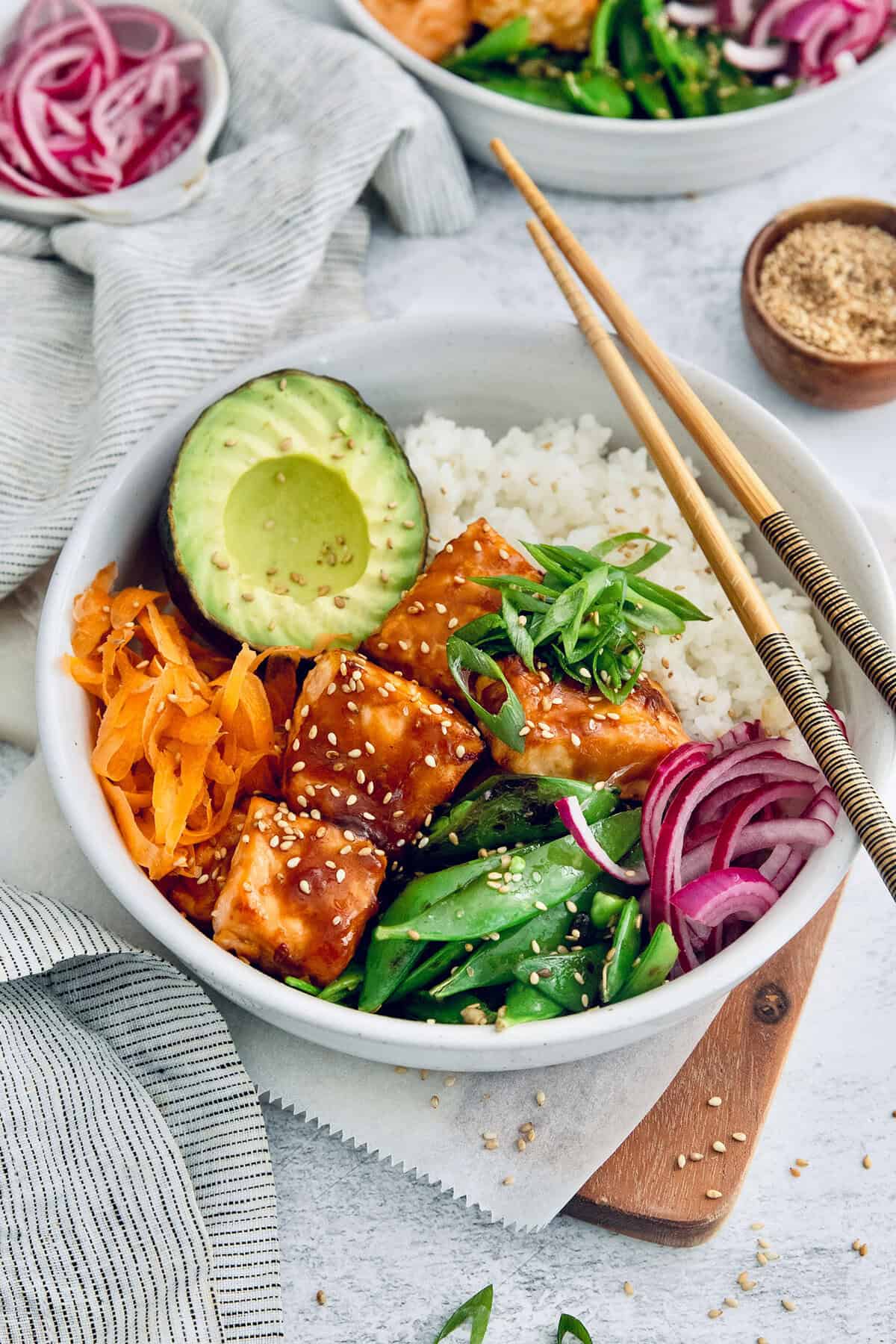 Teriyaki salmon bowls are an easy dinner ready in less than 20 minutes, with tender salmon, sticky teriyaki sauce, and lots of fresh veggies! Teriyaki salmon bowl with chopsticks set on top