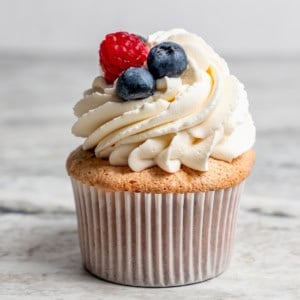 an angel food cupcake topped with white frosting and fresh berries