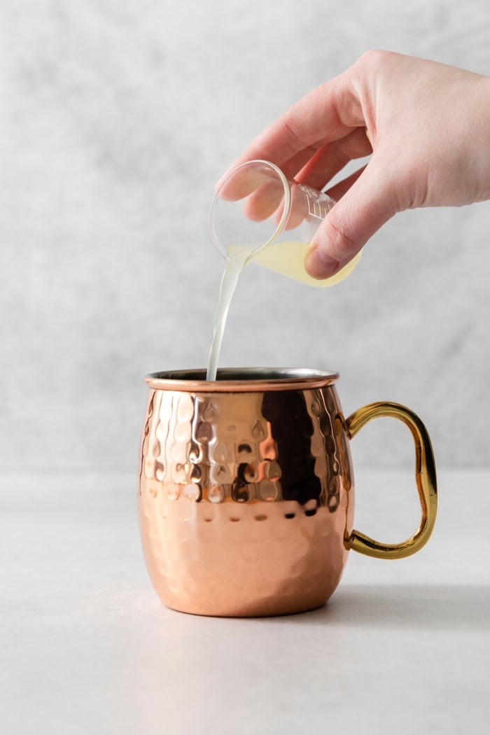 This classic Moscow mule recipe combines lime juice, ginger beer, and vodka with a sprig of fresh mint for a supremely refreshing cocktail! Pouring fresh lime juice into copper mug for Moscow mule
