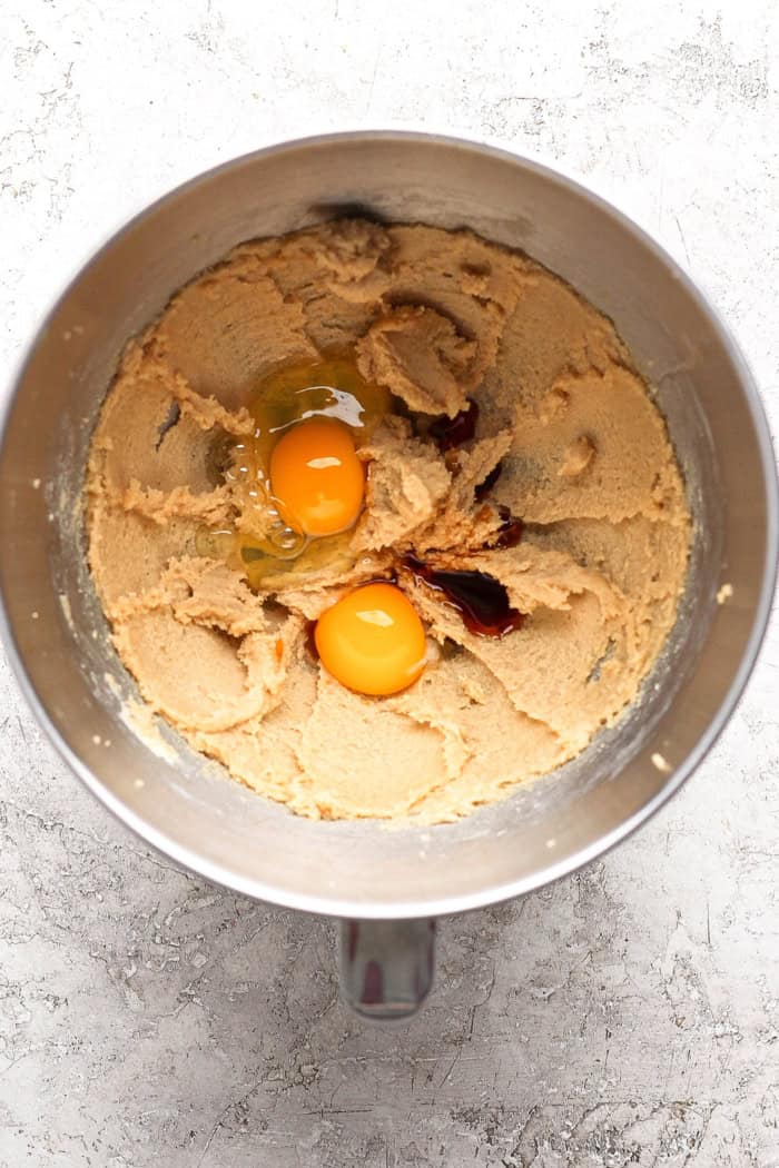 These easy Rhubarb Cookies are buttery, chewy, and a must-make for rhubarb season. White chocolate and flaky salt make them truly special! Egg and egg yolk cracked into bowl with vanilla and creamed butter and sugar