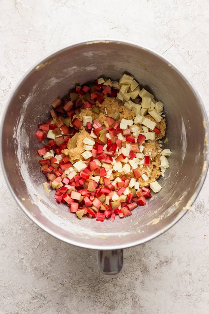 These easy Rhubarb Cookies are buttery, chewy, and a must-make for rhubarb season. White chocolate and flaky salt make them truly special! Overhead view of rhubarb and white chocolate added to bowl of cookie dough
