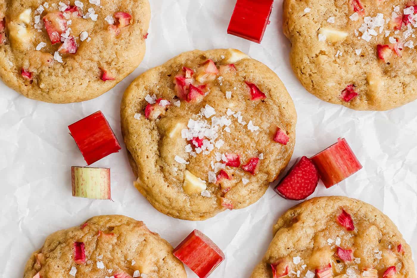 These easy Rhubarb Cookies are buttery, chewy, and a must-make for rhubarb season. White chocolate and flaky salt make them truly special! Overhead view of rhubarb cookies topped with flaky sea salt