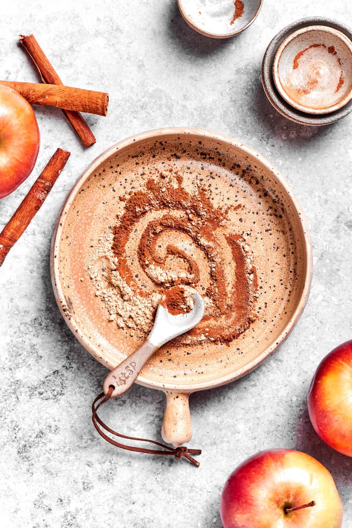 Apple Pie Spice brings some fall magic to all kinds of recipes and my version is a slightly different blend with extra warmth and coziness! Overhead view of apple pie spice mixture in bowl with measuring spoon