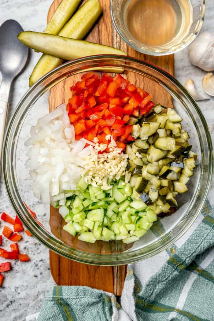 Inspired by Grillo's, this Pickle de Gallo recipe is oh so easy to make and packs in big, briny pickle flavor. Use it as a dip or condiment! Overhead view of ingredients for pickle de gallo in glass bowl