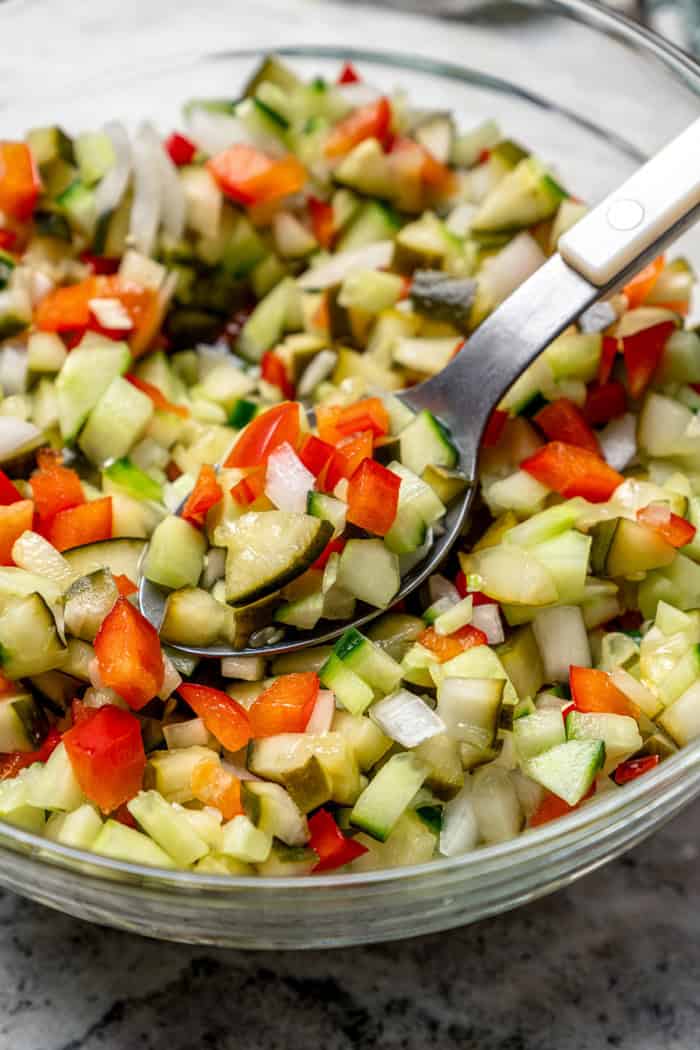 Inspired by Grillo's, this Pickle de Gallo recipe is oh so easy to make and packs in big, briny pickle flavor. Use it as a dip or condiment! a spoon in a bowl of pickle de gallo