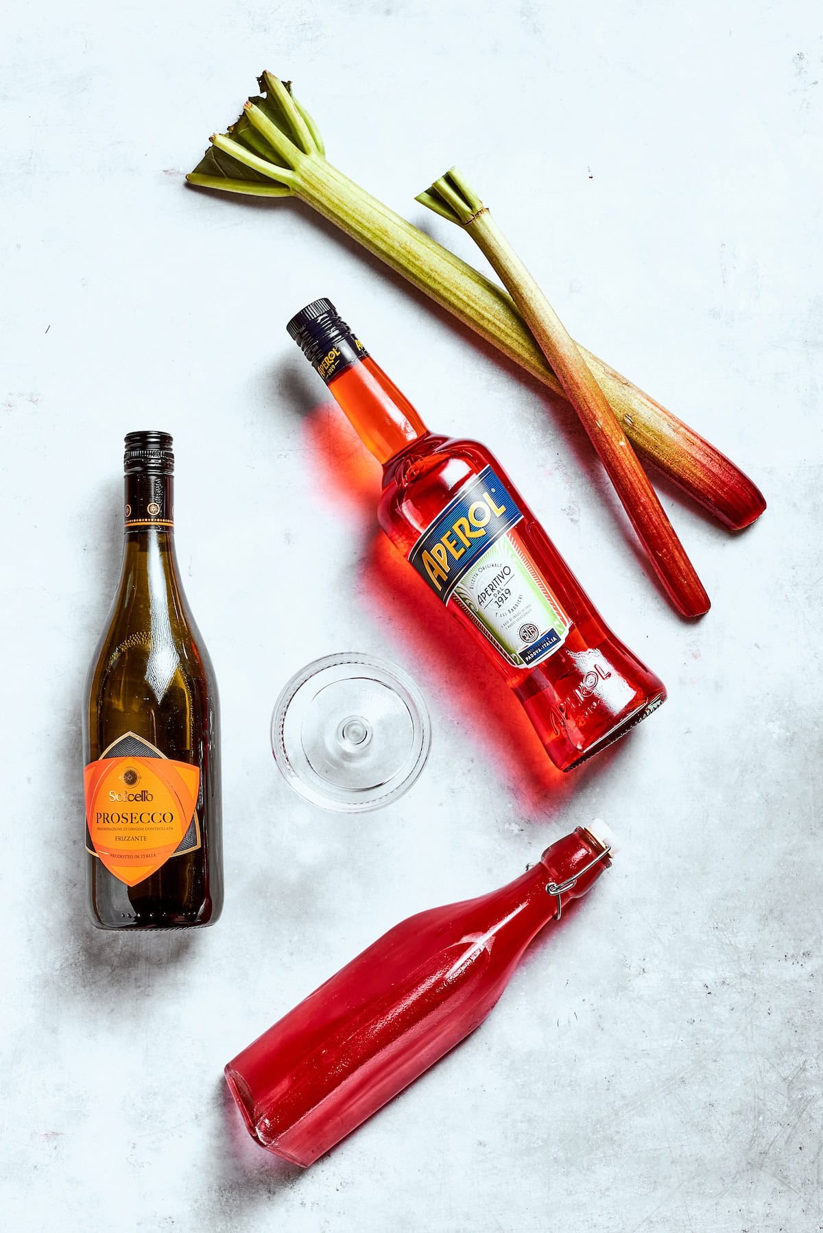 Midwest meets Italy in this summery Rhubarb Aperol Spritz! It’s a light, sparkling and refreshing cocktail perfect for using up fresh rhubarb. Overhead view of ingredients for rhubarb aperol spritz