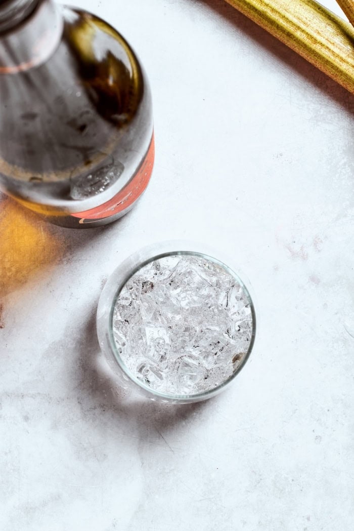 Midwest meets Italy in this summery Rhubarb Aperol Spritz! It’s a light, sparkling and refreshing cocktail perfect for using up fresh rhubarb. Overhead view of prosecco poured into glass of ice